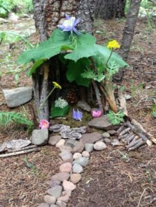 Outdoor fairy house made of plants in front of tree 