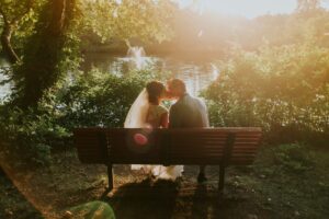 newlyweds kissing on park bench